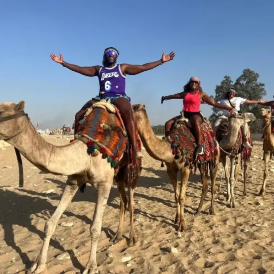 Travelers enjoying a camel ride near the Giza Pyramids during a 5 Days Cairo Aswan and Abu Simbel Tour Package
