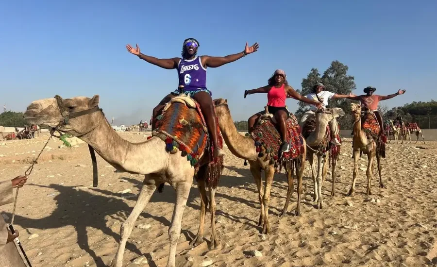 Travelers enjoying a camel ride near the Giza Pyramids during a 5 Days Cairo Aswan and Abu Simbel Tour Package