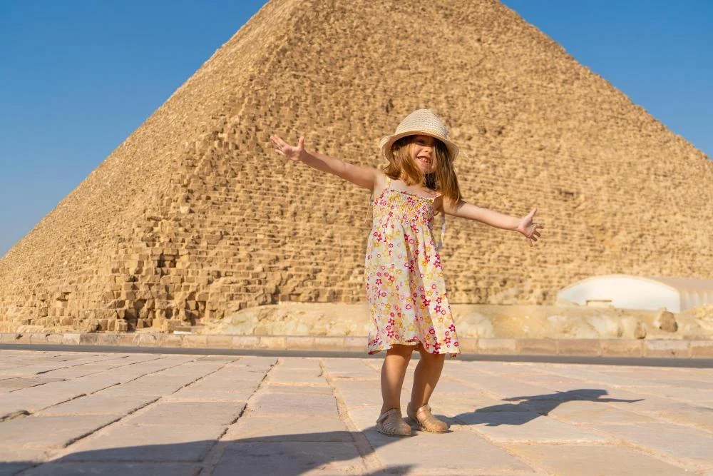 Young girl smiling in front of the Great Pyramids in Cairo, a safe destination for travelers.