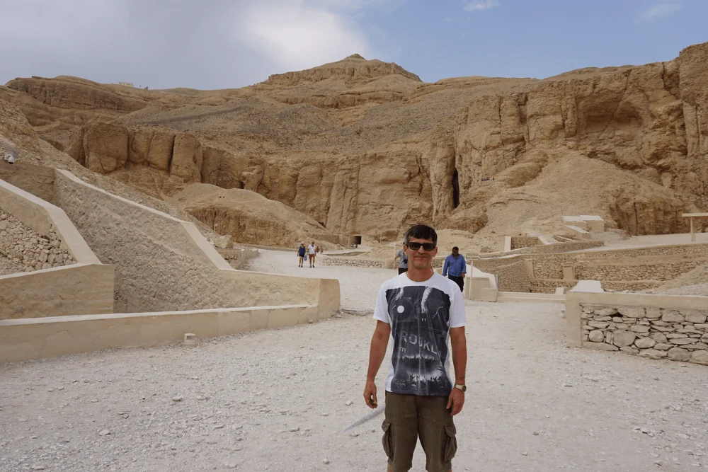 Visitor standing near the entrance area of the Valley of the Kings in Luxor, surrounded by desert cliffs.