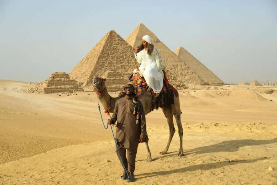 Couple enjoys a romantic sunset camel ride in the Egyptian desert.