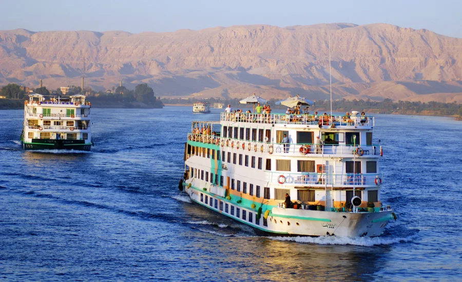 5 Days Nile River Cruise from El Gouna - A scenic view of the Nile River with a cruise ship sailing through it.