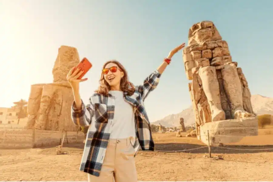 Traveler taking a photo near the Colossi of Memnon in Luxor, Egypt