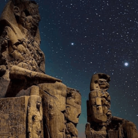 The Colossi of Memnon illuminated at night in Luxor.