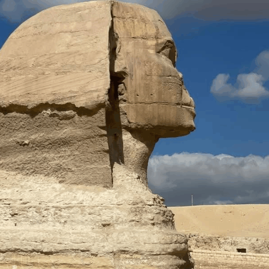 The Great Sphinx of Giza standing beside the pyramids under a clear sky.