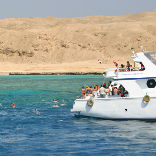 People snorkeling in Hurghada with a large boat nearby, Egypt