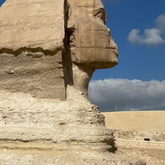 An elderly man standing in front of the Great Sphinx of Giza in the morning