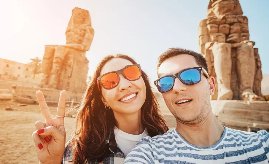 Couple taking a selfie in front of the Colossi of Memnon during our 10 Days Cairo, Nile Cruise & Alexandria Family Tour