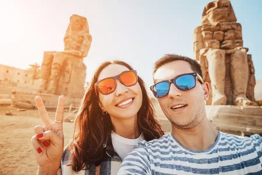 Couple taking a selfie in front of the Colossi of Memnon during our 10 Days Cairo, Nile Cruise & Alexandria Family Tour