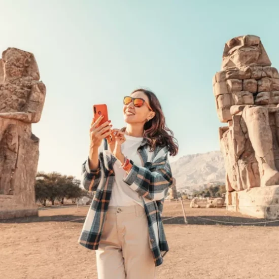 Tourist standing in front of the Colossi of Memnon as a part of our 14 Days Egypt Family Tour