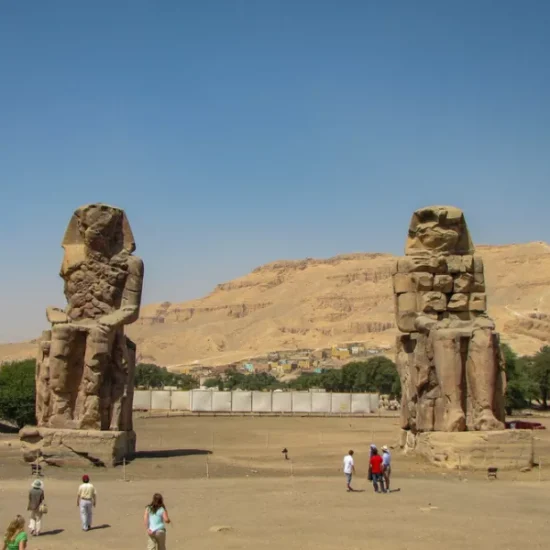 Tourists standing in front of the Colossi of Memnon