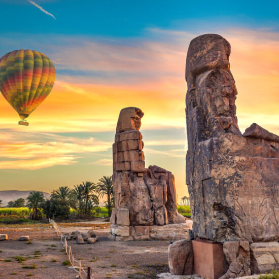 Tourists at the Colossi of Memnon with a hot air balloon above