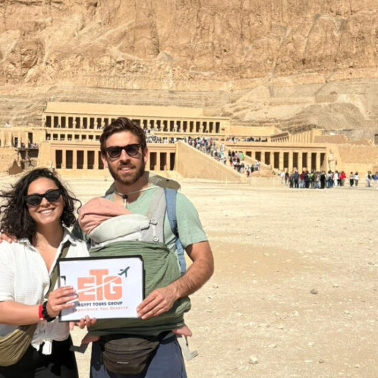 Couple holding Egypt Tours Group sign at Hatshepsut Temple