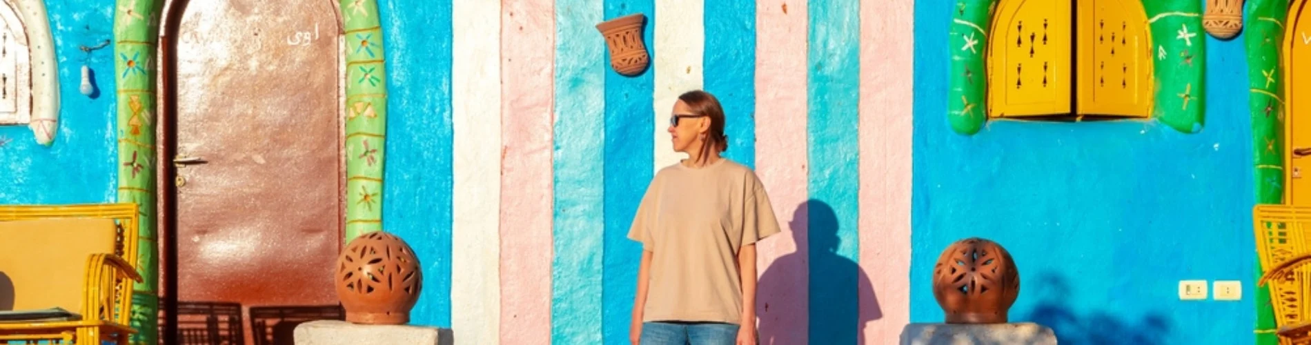 Tourist standing in front of a colorful Nubian house
