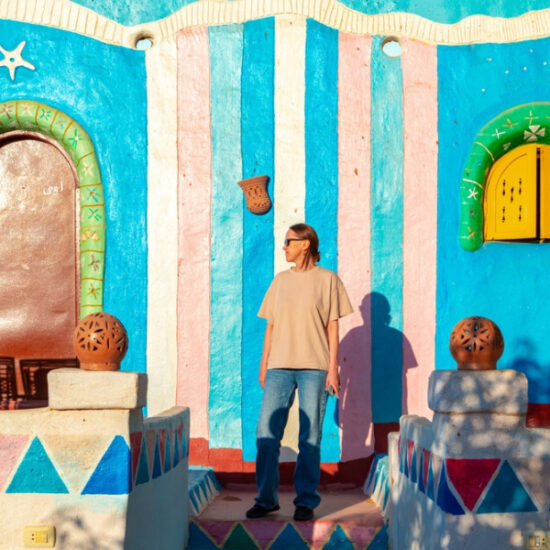 Tourist standing in front of a colorful Nubian house