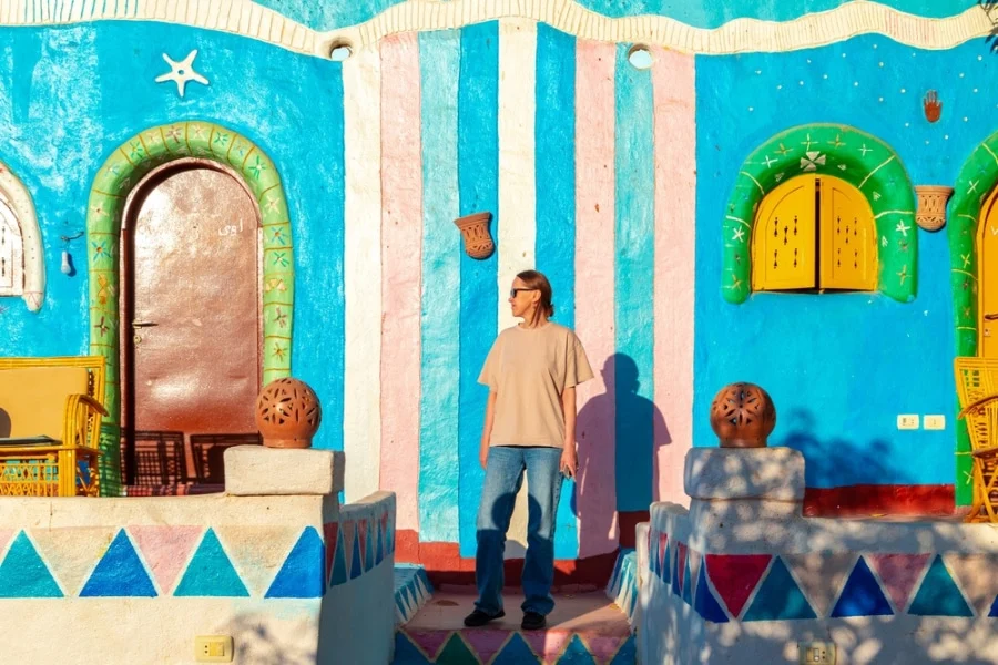 Tourist standing in front of a colorful Nubian house
